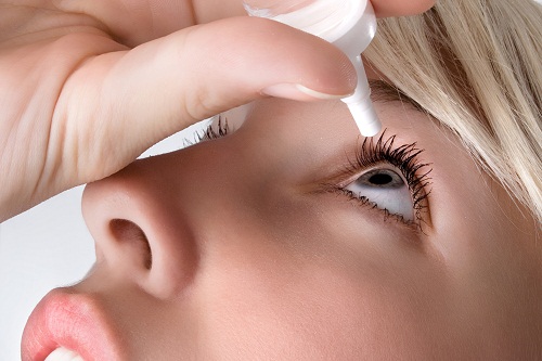 woman applying eyedroppes, close up